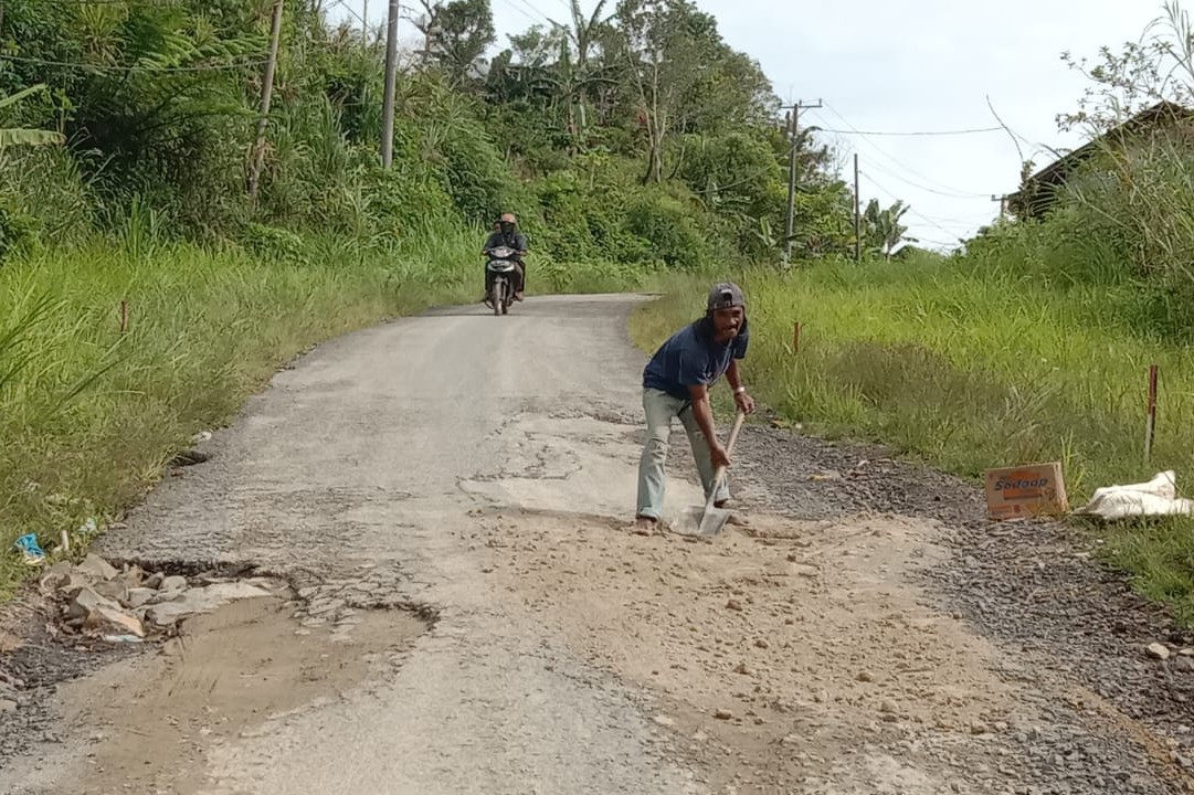 Warga  Pampangan Tambal Jalan Sembari Tunggu Perbaikan Permanen