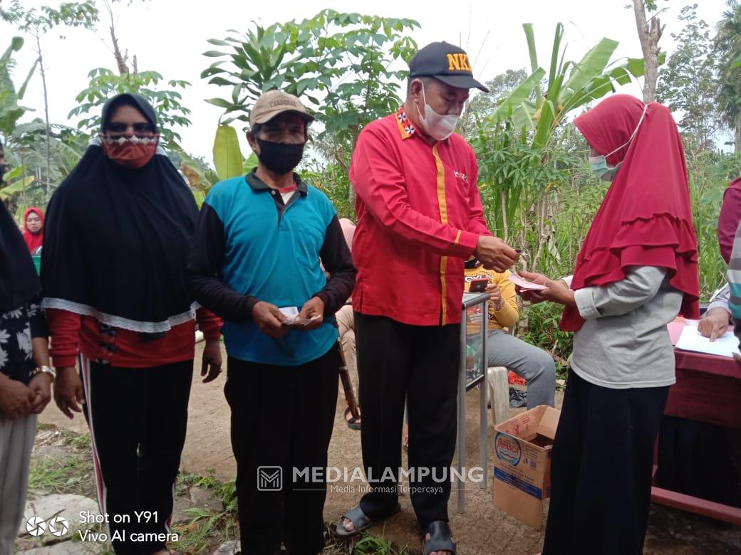 Ajak Warga Tingkatkan Imun, Peratin Sumberalam Bagikan BLT-DD di Areal Makam 